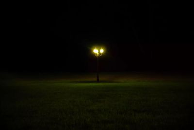 Illuminated field against sky at night