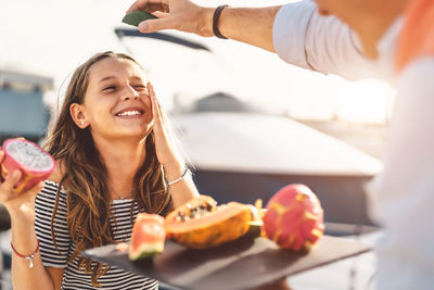 Smiling girl with father holding pitaya sitting outdoors