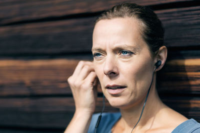 Mature woman using hands-free device outside log cabin