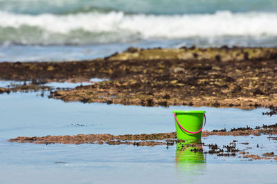 Bright green bucket by the ocean