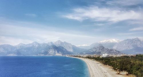 Scenic view of sea and mountains against blue sky