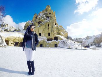 Smiling mid adult woman standing on snow covered field against castle