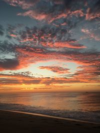 Scenic view of sea against dramatic sky during sunset