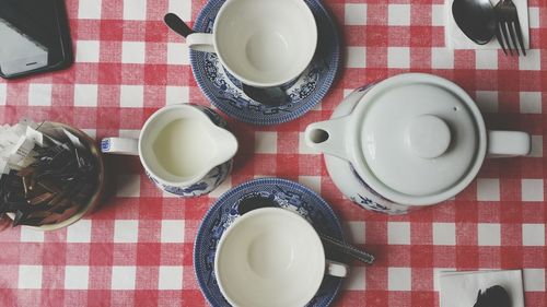 High angle view of teapot by cups and saucer on table