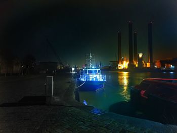 Illuminated harbor by sea against sky at night