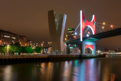 Illuminated bridge over river at night