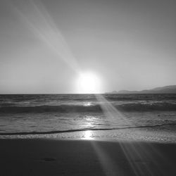 Sunlight streaming on sea against sky