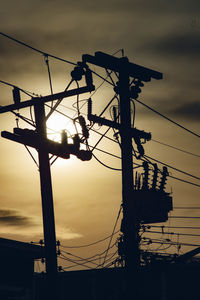 Low angle view of electricity pylon against sky during sunset