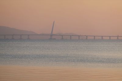 Bridge over sea against sky during sunset