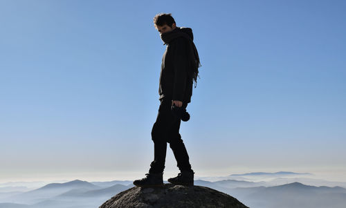 Woman standing on mountain against clear blue sky