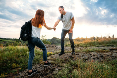 Friends standing on field against sky during sunset