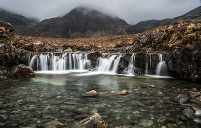 Scenic view of waterfall against sky