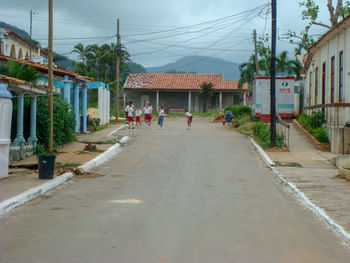 People walking on road amidst buildings against sky