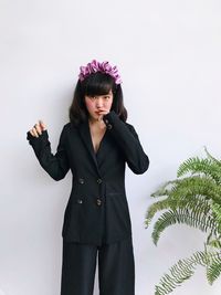 Portrait of young woman standing against white background