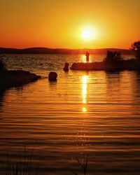 Scenic view of lake against orange sky