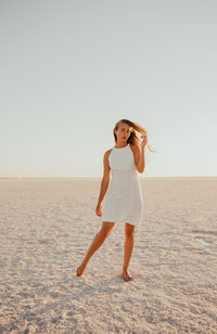 Full length of woman standing at beach against clear sky