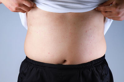 Midsection of woman standing against gray background