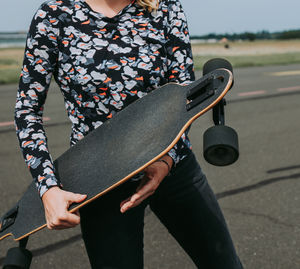 Midsection of woman holding skateboard