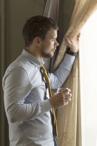 Side view of young man looking through window