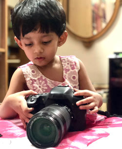 Close-up of girl holding digital camera on bed