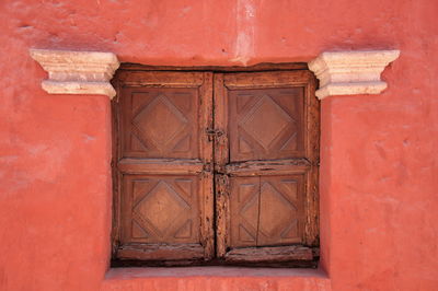 Wooden rustic window on red building wall