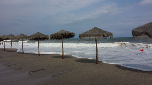 Deck chairs on beach against sky