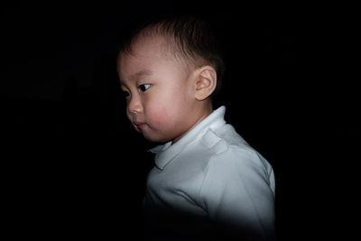 Close-up of boy against black background