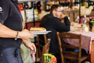 Midsection of waiter holding food while standing in restaurant