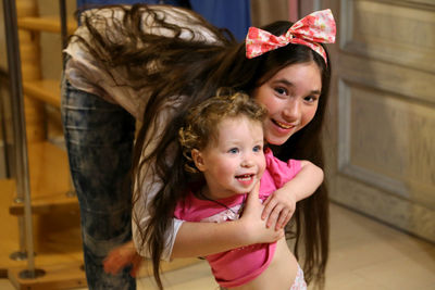 Portrait of teenage girl playing with baby girl at home