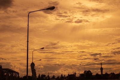 Low angle view of silhouette street light against dramatic sky