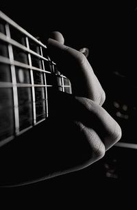 Hand playing guitar against black background