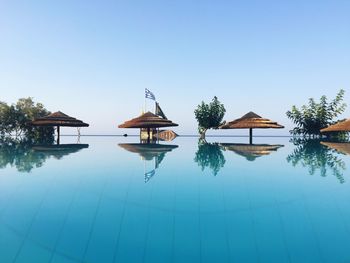 Thatched roof on infinity pool against blue sky