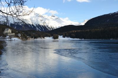 Scenic view of lake by snowcapped mountains against sky