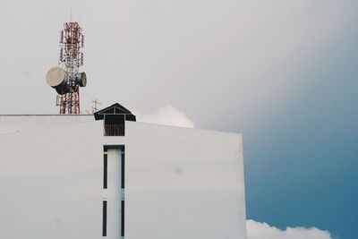 Low angle view of communications tower and building against sky