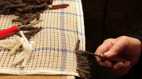 Cropped image of hand weaving carpet on table