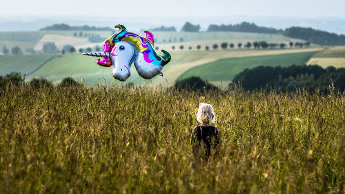 Stuffed toy on field against sky