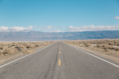 Road by desert against sky