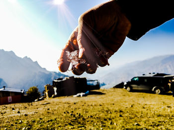 Midsection of person with umbrella on mountain against sky