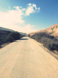 Empty road amidst land against sky