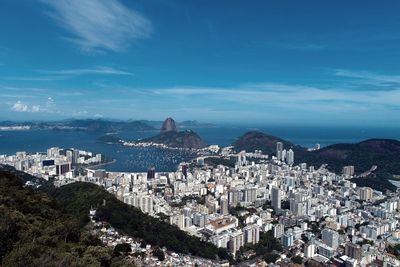 High angle view of townscape by sea against blue sky