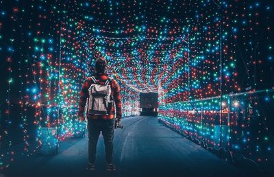 Full length of woman standing against illuminated lights at night