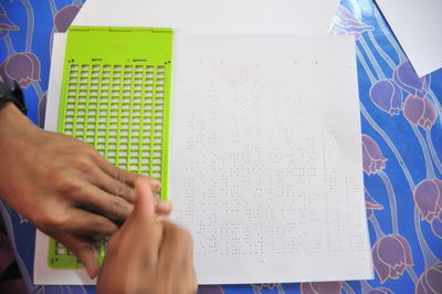 Cropped hand of man studying braille on table