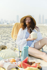 Happy woman with coconut enjoying sunny day at beach