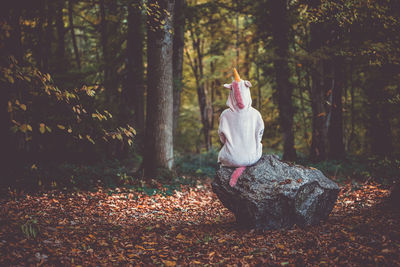 Girl sitting on tree trunk in forest