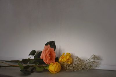 Scenic view of orange flower on table against wall