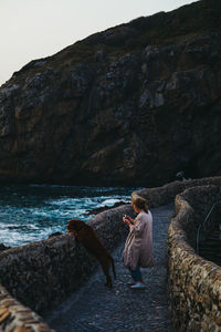 Woman on rock by sea against sky