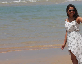 Portrait of smiling young woman standing on beach