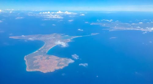 Aerial view of island amidst sea against blue sky