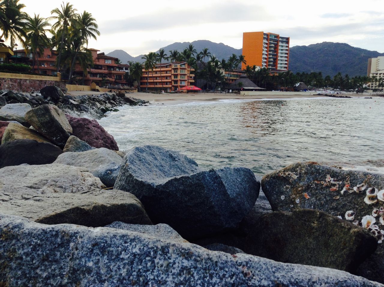 architecture, building exterior, water, built structure, sky, rock - object, sea, city, residential structure, residential building, house, residential district, cloud - sky, river, cloud, town, waterfront, rock, coastline, mountain