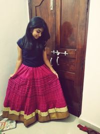 Portrait of young woman standing against door